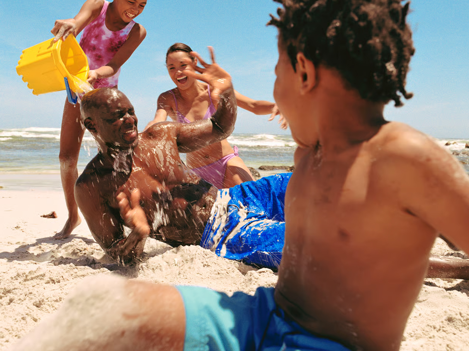A photograph of a family having fun playing on a sandy beach
