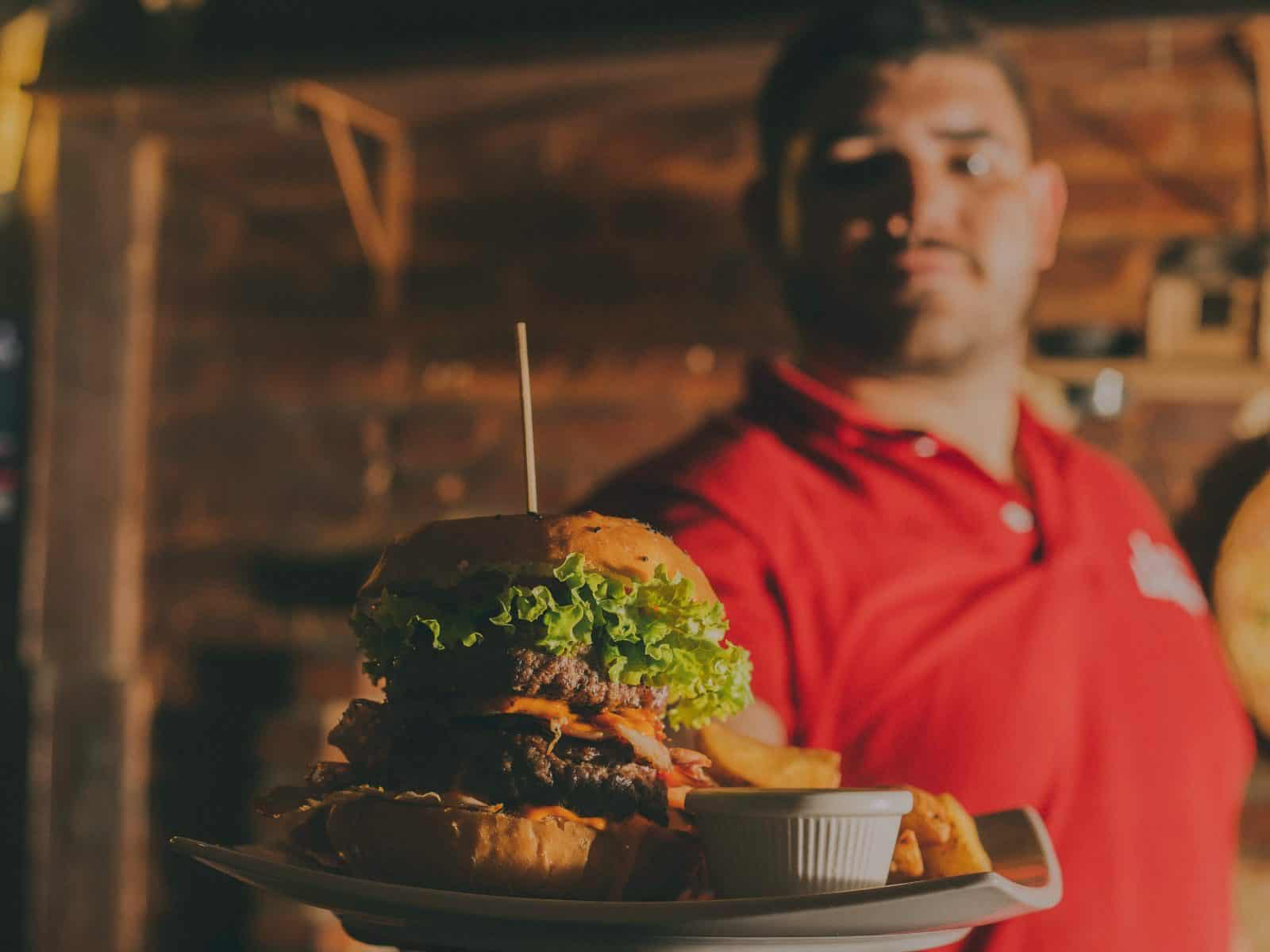 A waiter delivering a burger meal on a plate